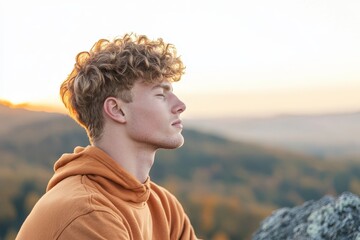 Wall Mural - Serene Gen Z Man Practicing Mindfulness Breathing on Mountain Peak - Digital Detox Concept