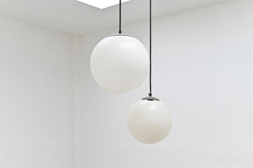 Minimalist white spherical pendant lights hanging from the ceiling in a modern interior setting..