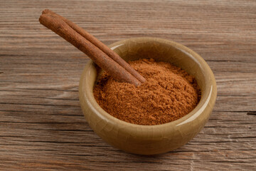 cinnamon powder and stick in a bowl on wooden table