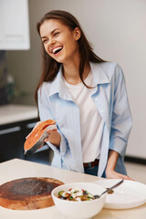 Wall Mural - Joyful woman preparing fresh salmon fillet in modern kitchen at home on wooden cutting board