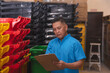 © Mdv Edwards - Middle aged warehouse clerk checking inventory in storage facility