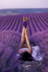 Wall Mural - Lavender field woman's legs emerging from the bushes, holding a bouquet of fragrant lavender. Purple lavender bushes in bloom, aromatherapy.