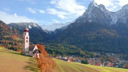 Poster - 4k drone flight moving to the side footage (Ultra High Definition) of St. Valentin ( Kastelruth ) church with Petz peak on background. Picturesque autumn scene of Kastelruth village, Italy.