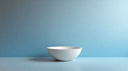 A white bowl sits on a table in front of a blue wall