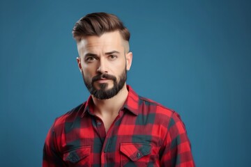 Wall Mural - Close-up portrait of a young man with a beard wearing a red and black plaid shirt