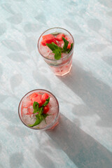 Homemade summer watermelon lemonade with ice and mint on light background, place for text