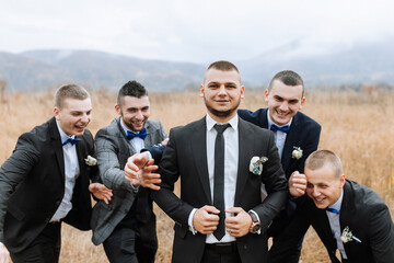 Wall Mural - A group of men in suits and ties are posing for a photo. They are all smiling and seem to be enjoying themselves. Scene is lighthearted and fun, as the men are posing for a group photo in a field