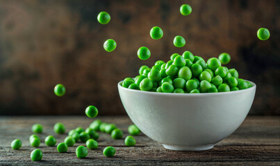 Wall Mural - Green peas falling into white bowl on rustic wooden background