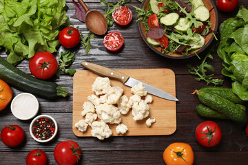 Wall Mural - Healthy vegetarian food. Pieces of cauliflower, salad, peppercorns and vegetables on wooden table, flat lay