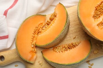 Cut ripe Cantaloupe melon on white table, flat lay