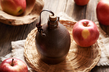 Sticker - A dark ceramic bottle of apple cider vinegar with fresh red apples