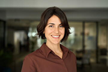 headshot close up face portrait of young happy smiling hispanic businesswoman, female company worker