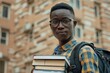 © Alexandr - Portrait of an African-American student with a backpack and books in his hands outside the university building.