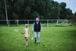 © amixstudio - Teenage girl playing badminton with her father on green grass in summer park