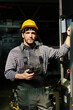© TrueFrame Collective - Industrial worker wearing safety gear operating heavy machinery in factory setting