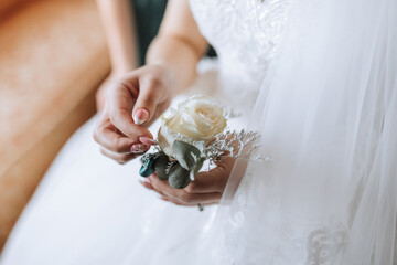 Wall Mural - A woman is holding a flower in her hand. The flower is white and has a green stem. The woman is wearing a wedding dress and is sitting on a chair. Concept of elegance and romance