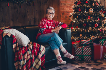 Sticker - Full length portrait of cheerful peaceful lady sitting cozy sofa christmas tree illumination loft interior apartment inside