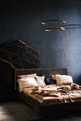 Wall Mural - Large bed with a black headboard, surrounded by pillows. Bedroom is dark and modern