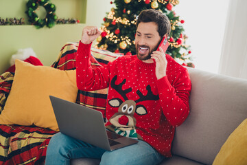 Canvas Print - Photo of nice young man speak phone raise fist laptop ugly sweater christmas atmosphere apartment indoors