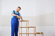 © New Africa - Worker with electric screwdriver assembling wooden shelving unit indoors