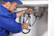 © New Africa - Professional plumber fixing piping system at home