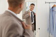 © New Africa - Handsome man in stylish suit looking at mirror indoors