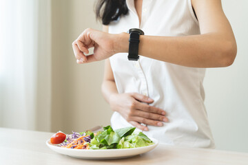 Wall Mural - Intermittent Fasting eat concept, Woman looking at meal waiting time to eat during intermittent fasting session