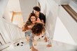 © Marko Geber - Family playing and laughing while climbing stairs indoors