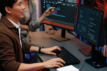 IT developers discussing with point to intelligent website development coder system running data online two screens information technology at neon light room at modern office. Infobahn.