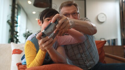 Grandfather and granddaughter together play console game, entertainment media. Old senior use technology communicate with new generation kid cross generation gap strengthen family bond. Divergence.