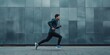© Andrii Zastrozhnov - A man runs on a sidewalk in front of a wall. The man is wearing a blue jacket and black pants