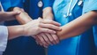 © Felippe Lopes - A group of medical professionals place their hands together in a gesture of teamwork.