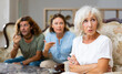 © JackF - Dissatisfied mother-in-law siting on a chair against of a confused husband and wife on the sofa in the living room at home