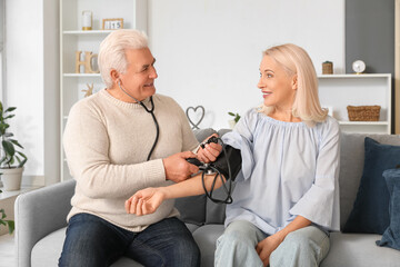 Canvas Print - Mature man measuring blood pressure of his wife at home