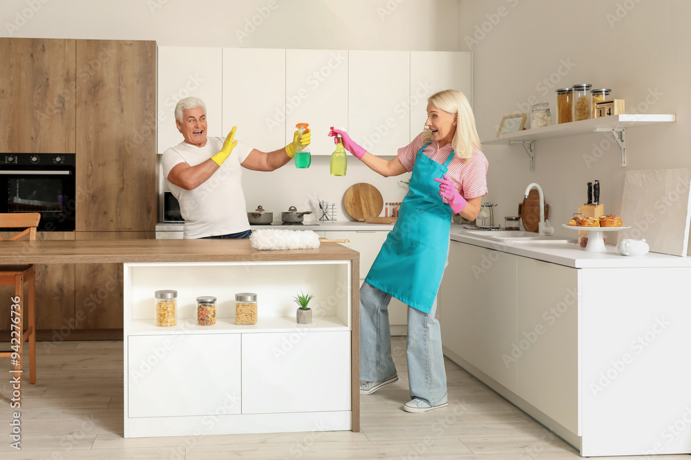 Mature couple having fun while cleaning in kitchen