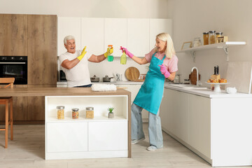 Wall Mural - Mature couple having fun while cleaning in kitchen