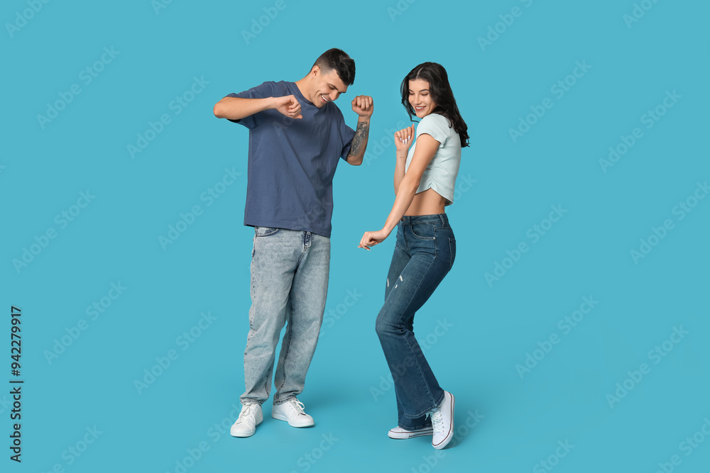 Happy young couple dancing on blue background