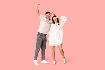 Poster - Happy young couple dancing on pink background