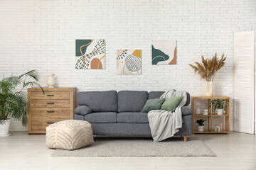 Sticker - Interior of beautiful living room with comfortable sofa, pouf, chest of drawers and pictures