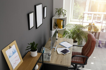 Wall Mural - Interior of office with workplace, armchair, modern computer, houseplant and shelving unit near black wall