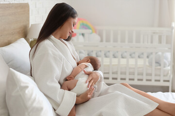 Sticker - Beautiful young happy woman in bathrobe breastfeeding her baby at home