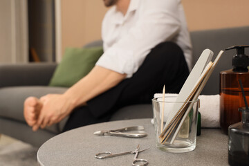 Poster - Handsome young man with tools doing pedicure at home, closeup