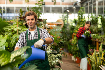 Wall Mural - Professional man florist withe plastic watering can in floral shop