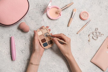 Wall Mural - Female hands with palette of eyeshadows, different cosmetic products  on light background, closeup