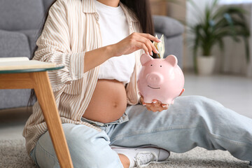 Poster - Young pregnant woman putting money into piggy bank on floor at home, closeup. Maternal Benefit concept