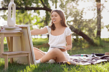 Wall Mural - Young woman painting on canvas in park