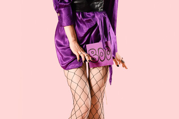 Wall Mural - Beautiful young woman dressed as witch for Halloween with word BOO on pink background, closeup