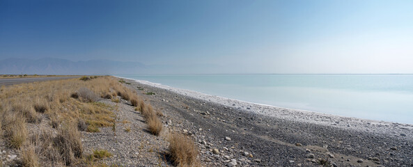 Great Salt Lake shore panorama with highway and distant mountain range contour in haze