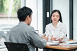 © Satori Studio - Two professionals engaged in a discussion during a business meeting in a modern office setting, focusing on documents and ideas.
