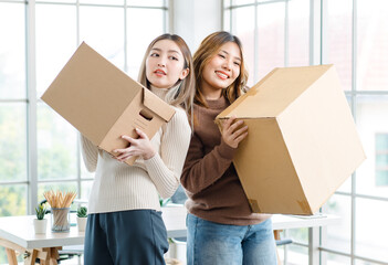 Portrait two roommates happy young Asian female moving packing things in box into new apartment, carry cardboard boxes, Concept teenage or friends, Real estate property buying, relocation, new home